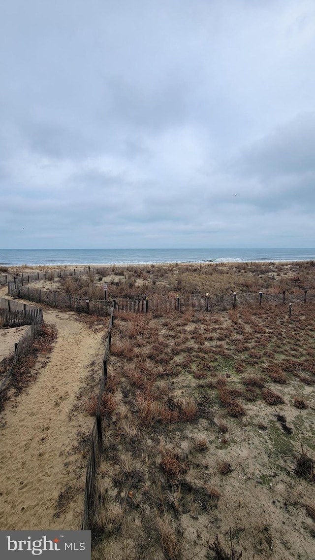 view of yard featuring a beach view, a water view, and fence