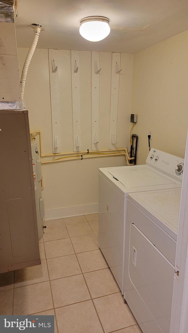 washroom with light tile patterned flooring, washer and dryer, and cabinet space