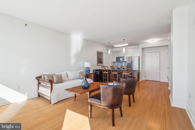 living area featuring light wood-style flooring and baseboards