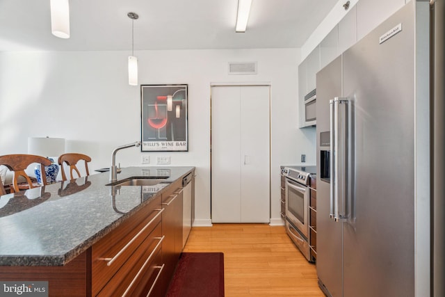 kitchen with visible vents, modern cabinets, stainless steel appliances, pendant lighting, and a sink