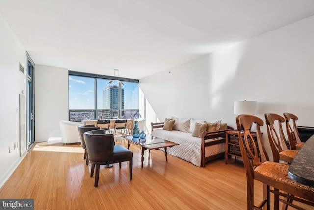 living area featuring a view of city, floor to ceiling windows, and light wood-style floors