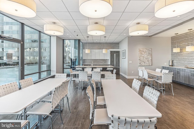 dining area featuring a paneled ceiling, floor to ceiling windows, baseboards, and dark wood finished floors