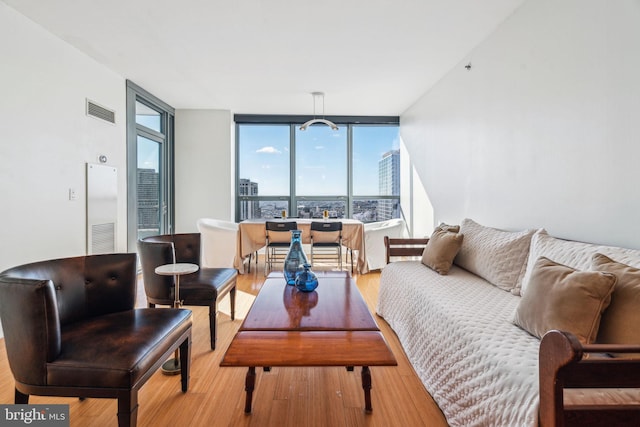 living area with a view of city, wood finished floors, visible vents, and floor to ceiling windows