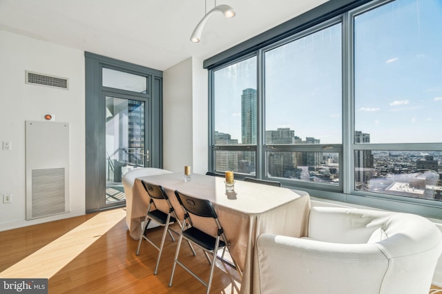 dining space with a view of city, wood finished floors, and visible vents