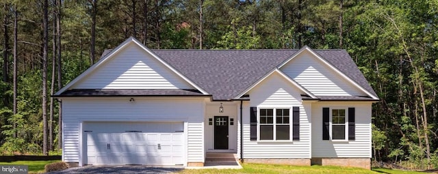 single story home featuring aphalt driveway, roof with shingles, entry steps, a wooded view, and a garage