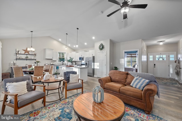 living area featuring light wood-style floors, recessed lighting, vaulted ceiling, and ceiling fan with notable chandelier