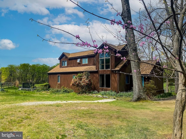 rear view of property featuring a trampoline and a yard