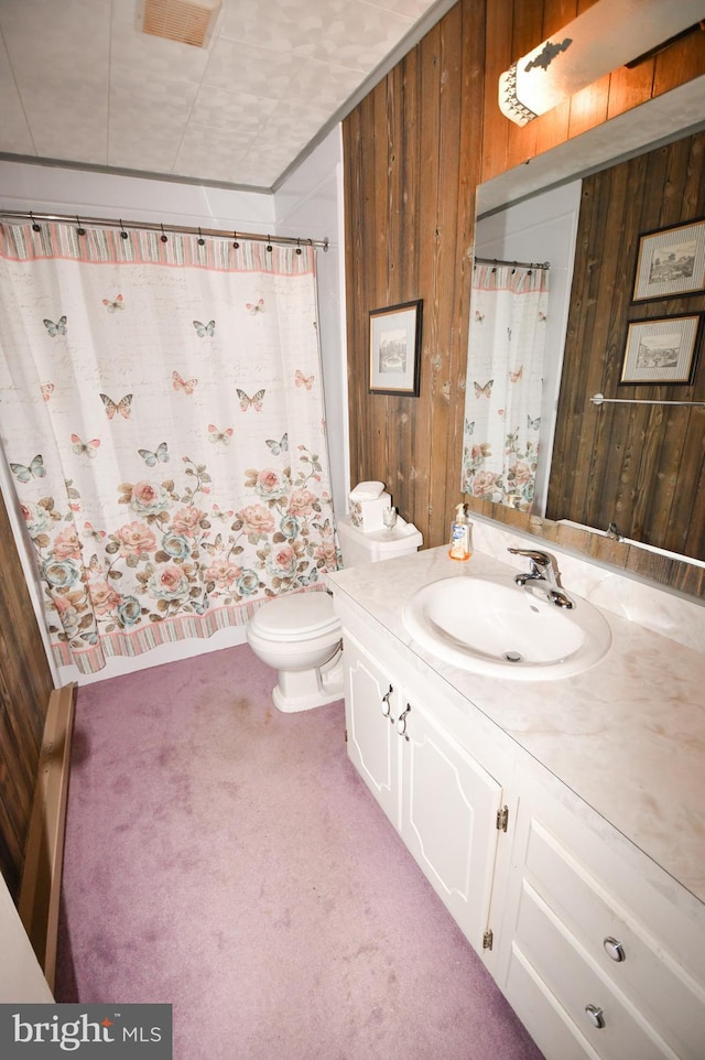 bathroom with vanity, wooden walls, and toilet