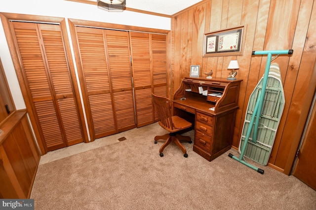 home office with light carpet and wood walls