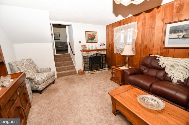 living room with a stone fireplace, light carpet, and wood walls