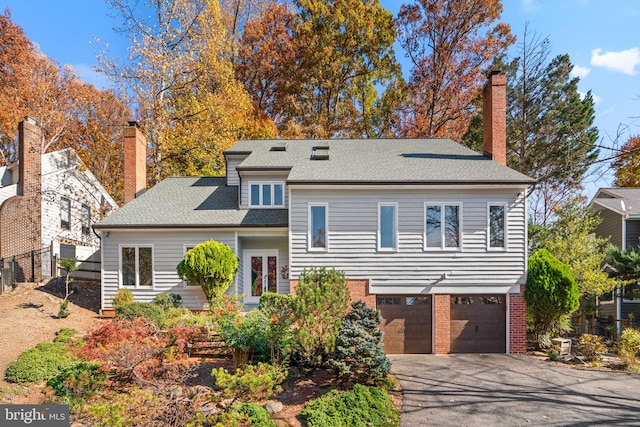 view of front of property featuring a garage, brick siding, a chimney, and driveway