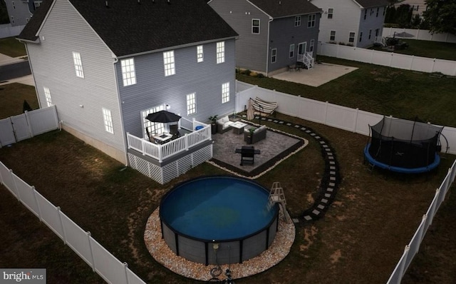 rear view of property with a fenced in pool, an outdoor living space, a trampoline, and a patio area