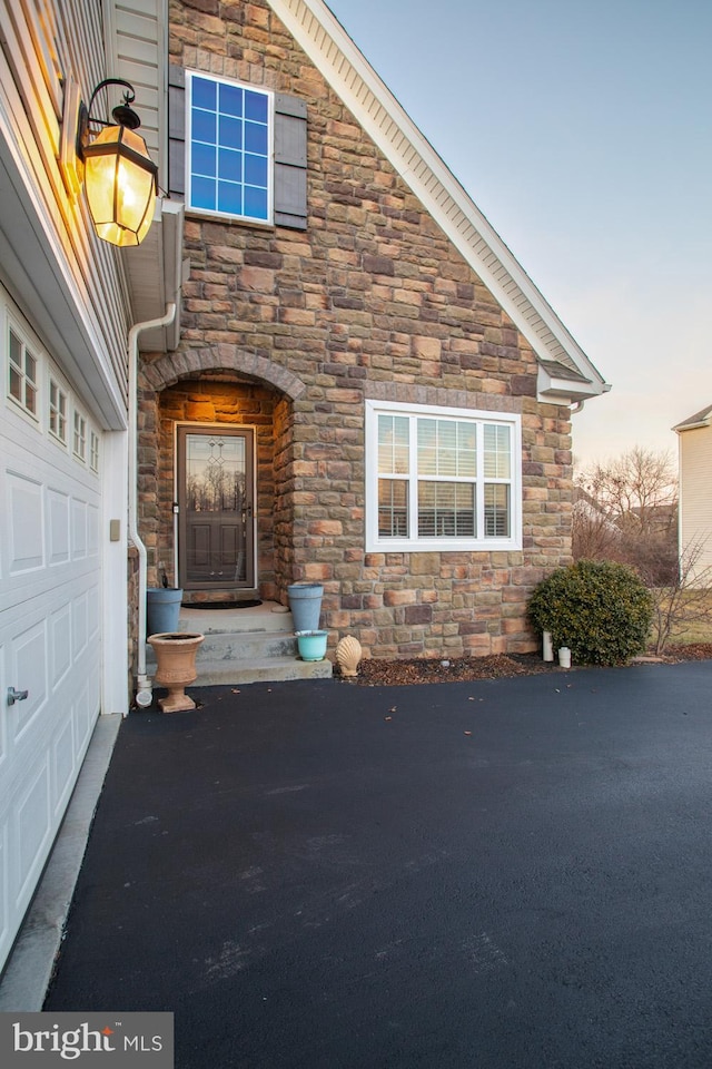 exterior entry at dusk featuring a garage