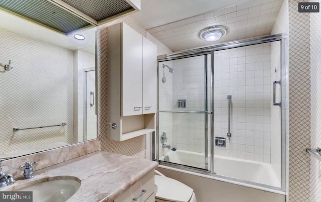 full bathroom featuring vanity, decorative backsplash, bath / shower combo with glass door, and toilet