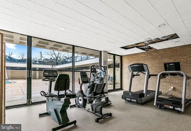 workout area featuring floor to ceiling windows and brick wall