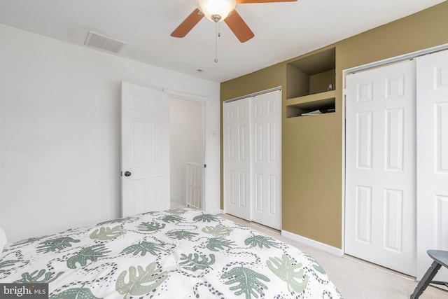 unfurnished bedroom with two closets, ceiling fan, and carpet flooring