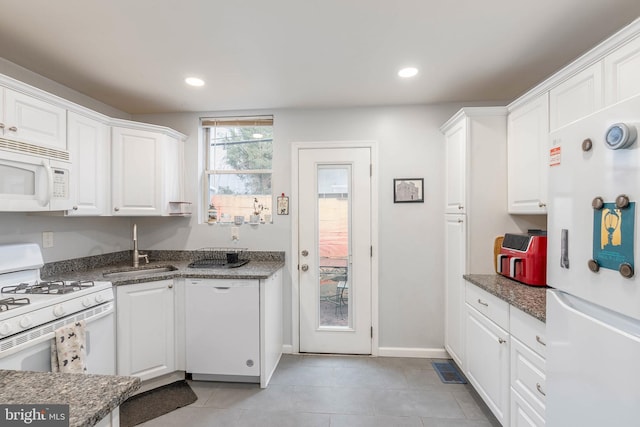 kitchen featuring white cabinetry, sink, white appliances, and dark stone countertops