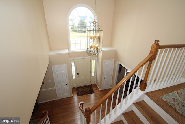 entrance foyer featuring a towering ceiling, dark hardwood / wood-style floors, and a chandelier