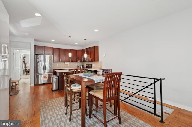 dining space with recessed lighting, a skylight, baseboards, and wood finished floors