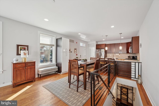 dining area with baseboards, light wood finished floors, visible vents, and recessed lighting