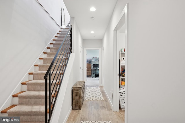 staircase with baseboards, wood finished floors, and recessed lighting