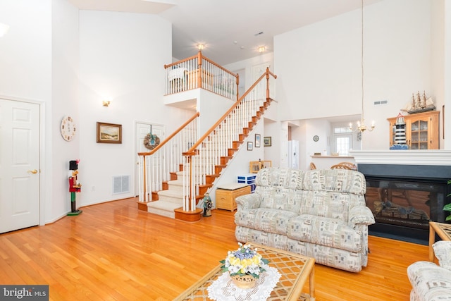 living room with hardwood / wood-style floors, a chandelier, and a high ceiling