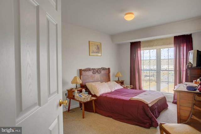 bedroom with baseboards and light colored carpet