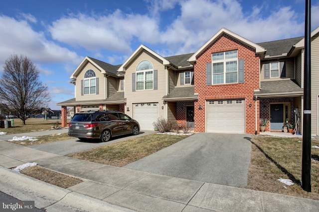 view of property with driveway, an attached garage, and brick siding