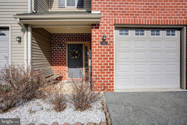 doorway to property with a garage and brick siding