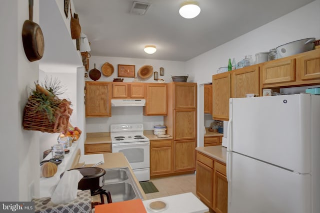 kitchen with white appliances, light tile patterned floors, visible vents, light countertops, and under cabinet range hood