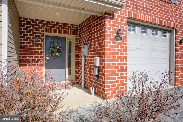 entrance to property featuring an attached garage and brick siding