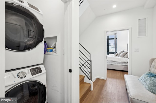 laundry area featuring stacked washing maching and dryer and hardwood / wood-style floors