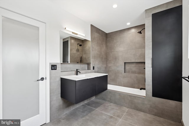 bathroom with vanity, tile patterned floors, tile walls, and walk in shower