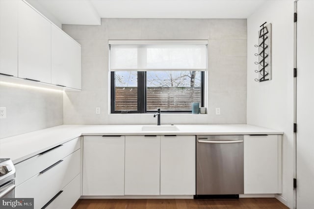 kitchen with appliances with stainless steel finishes, sink, white cabinets, and dark hardwood / wood-style flooring