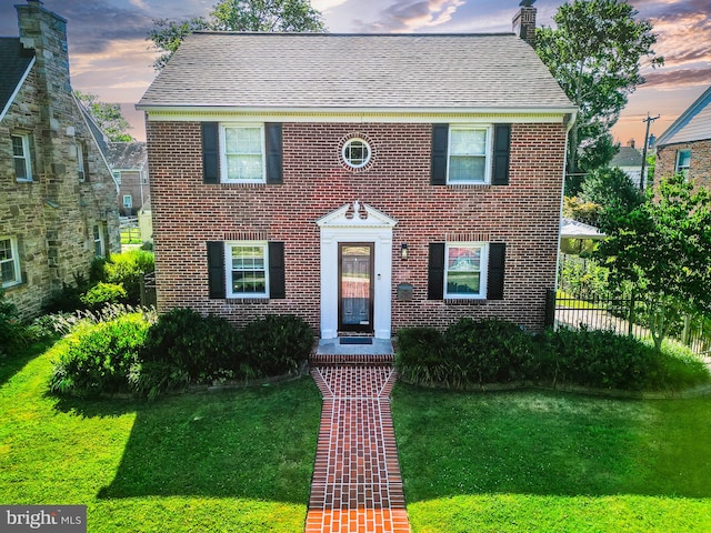 view of front of home with a front yard, fence, and brick siding