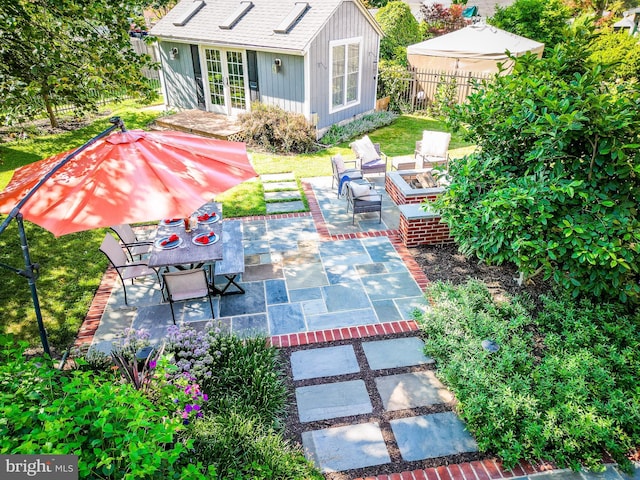 view of patio with french doors, an outdoor fire pit, fence, and outdoor dining area