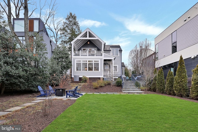 rear view of property featuring a balcony, a lawn, and a fire pit