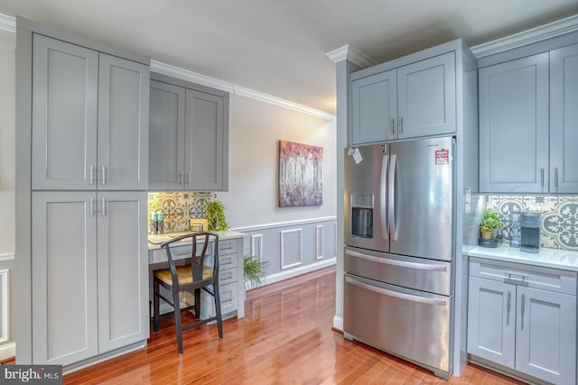 103 Candor Ln, Dover, DE 19901 - kitchen with light wood finished floors, ornamental molding, built in study area, stainless steel fridge with ice dispenser, and tasteful backsplash