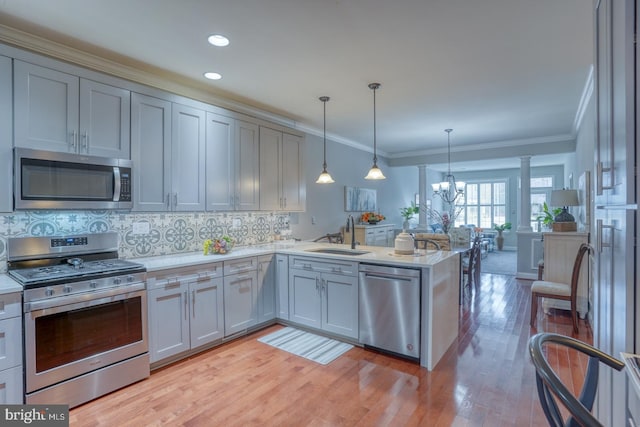 103 Candor Ln, Dover, DE 19901 - kitchen featuring appliances with stainless steel finishes, ornamental molding, a sink, light countertops, and a notable chandelier