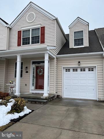 view of front facade featuring driveway, a garage, and a porch