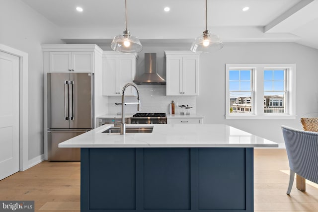 kitchen featuring high end refrigerator, light wood-style flooring, wall chimney range hood, white cabinetry, and backsplash