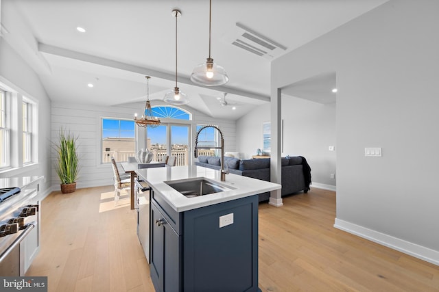 kitchen featuring lofted ceiling, light countertops, hanging light fixtures, a sink, and light wood-type flooring