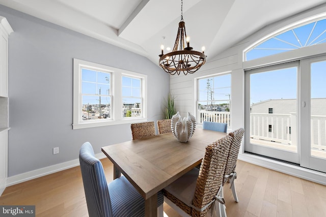 dining area with a notable chandelier, a healthy amount of sunlight, lofted ceiling, and light wood-style floors