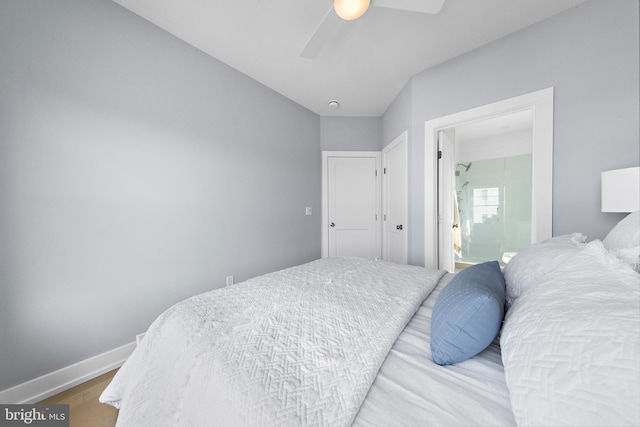 bedroom with a ceiling fan, ensuite bath, baseboards, and wood finished floors