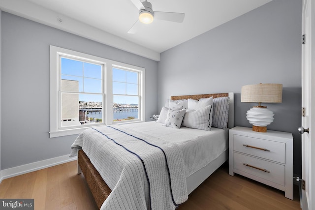 bedroom with a water view, ceiling fan, baseboards, and wood finished floors