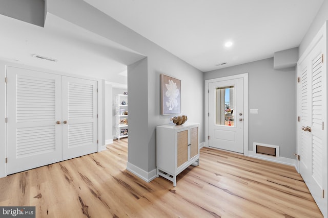 foyer with light wood-style flooring, visible vents, and baseboards