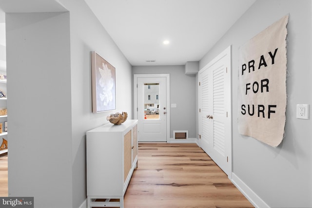 hallway featuring light wood-type flooring, visible vents, and baseboards