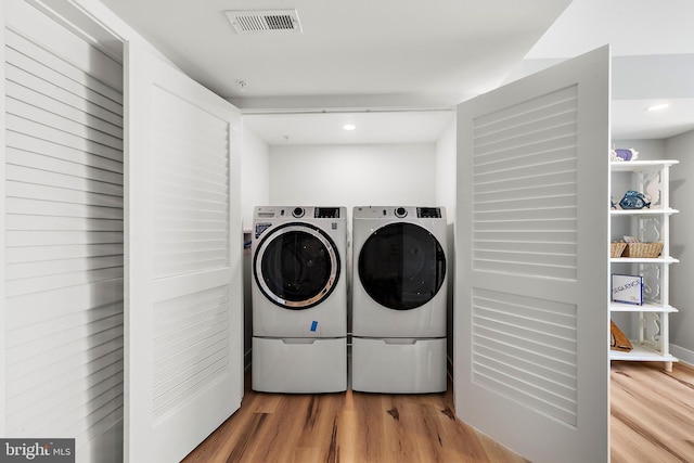 clothes washing area featuring laundry area, visible vents, washing machine and clothes dryer, and wood finished floors