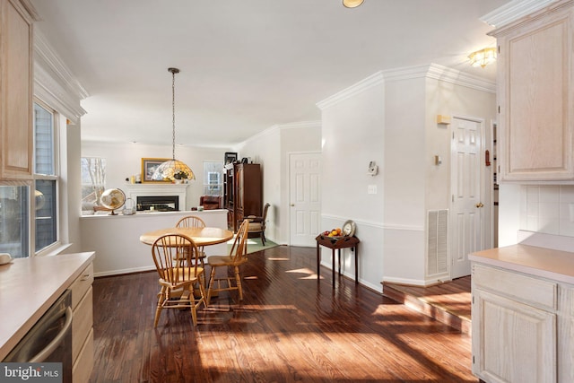 dining space featuring dark hardwood / wood-style flooring, crown molding, and a wealth of natural light