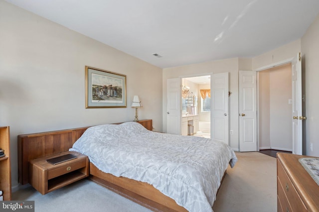 bedroom featuring connected bathroom and light colored carpet